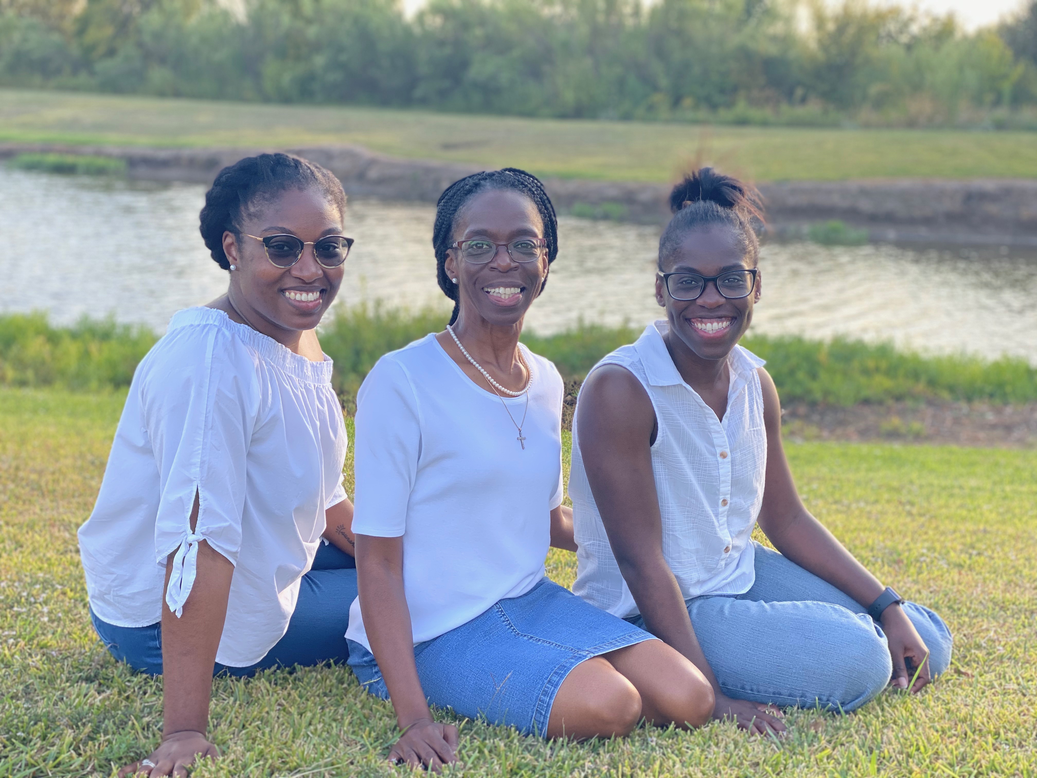 image2 Three young women sitting on the grass near a body of water.